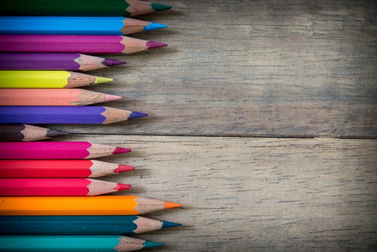 Colored pencils and note book on a wooden